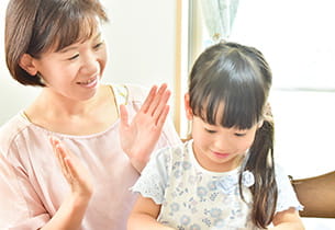 女性の先生が女の子にそろばんを教えているイメージ